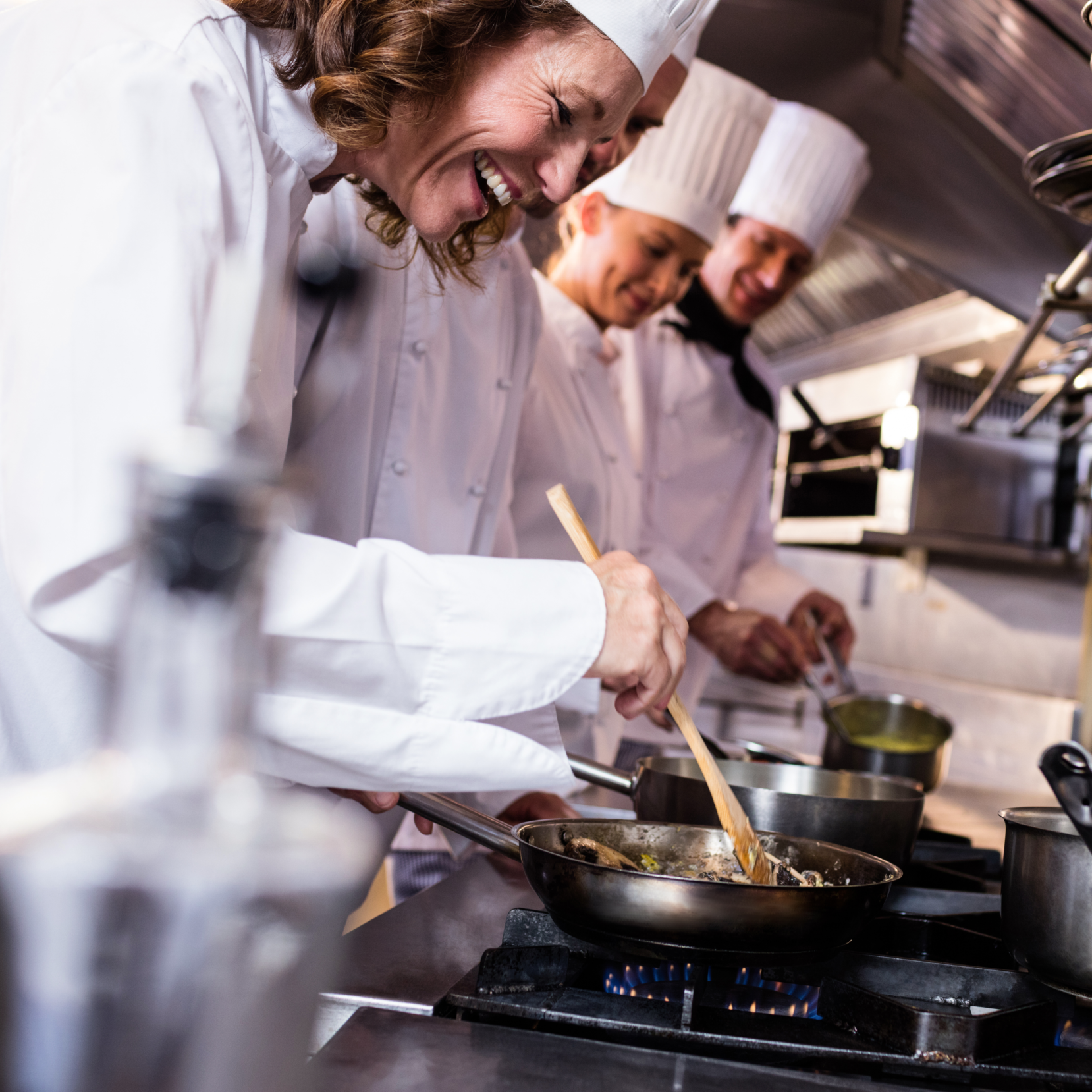 chefs using a commercial gas hob to cook instead of a commercial induction hob